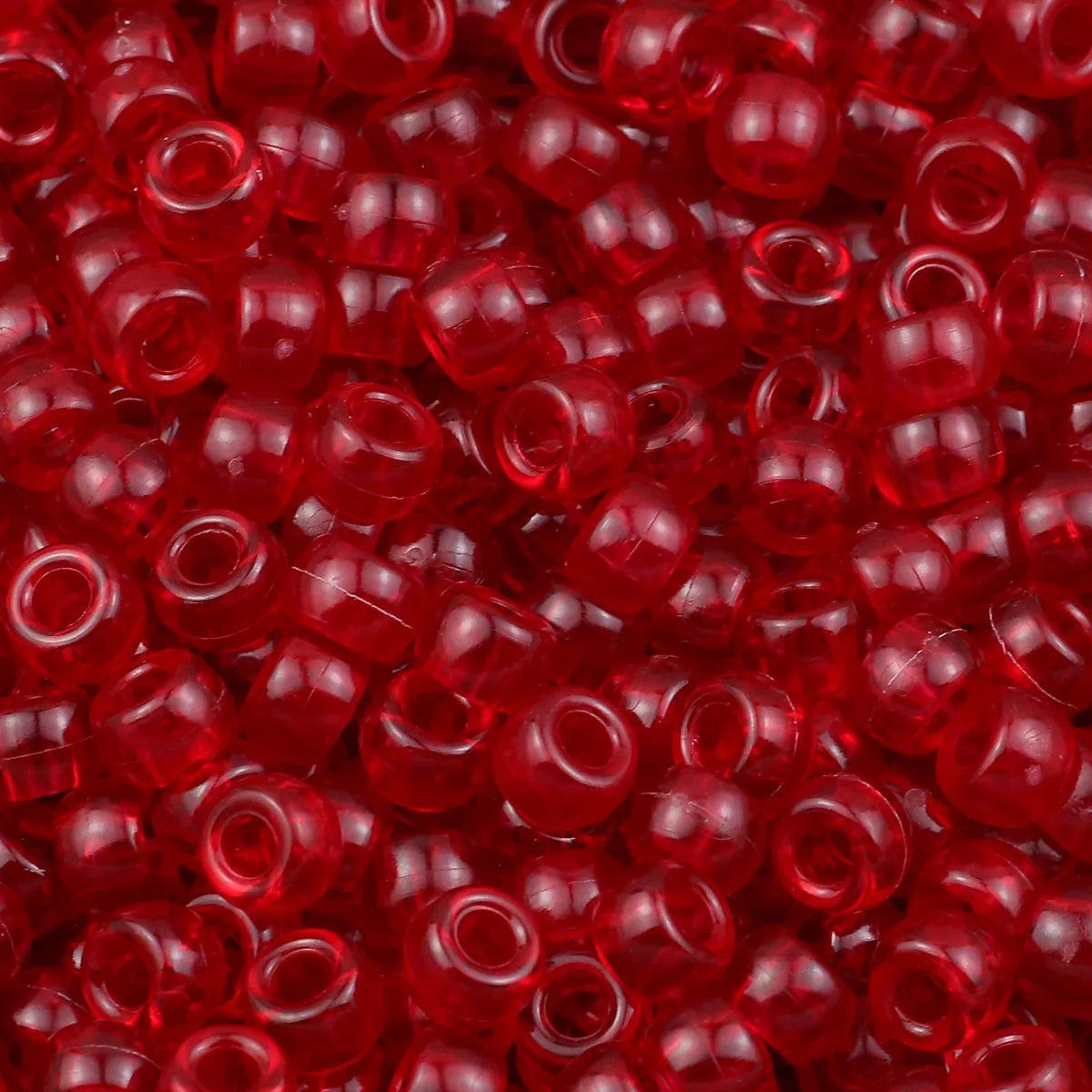 A close-up view of small, translucent red pony beads for jewelry making and craft projects.