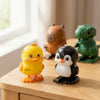 A collection of wind-up animal toys including a yellow chick, a brown bear, and a black penguin, displayed on a wooden surfac