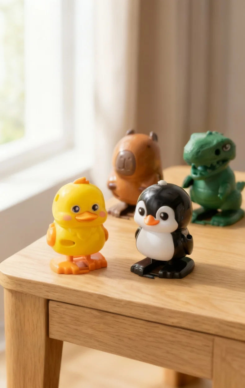 A collection of wind-up animal toys including a yellow chick, a brown bear, and a black penguin, displayed on a wooden surfac