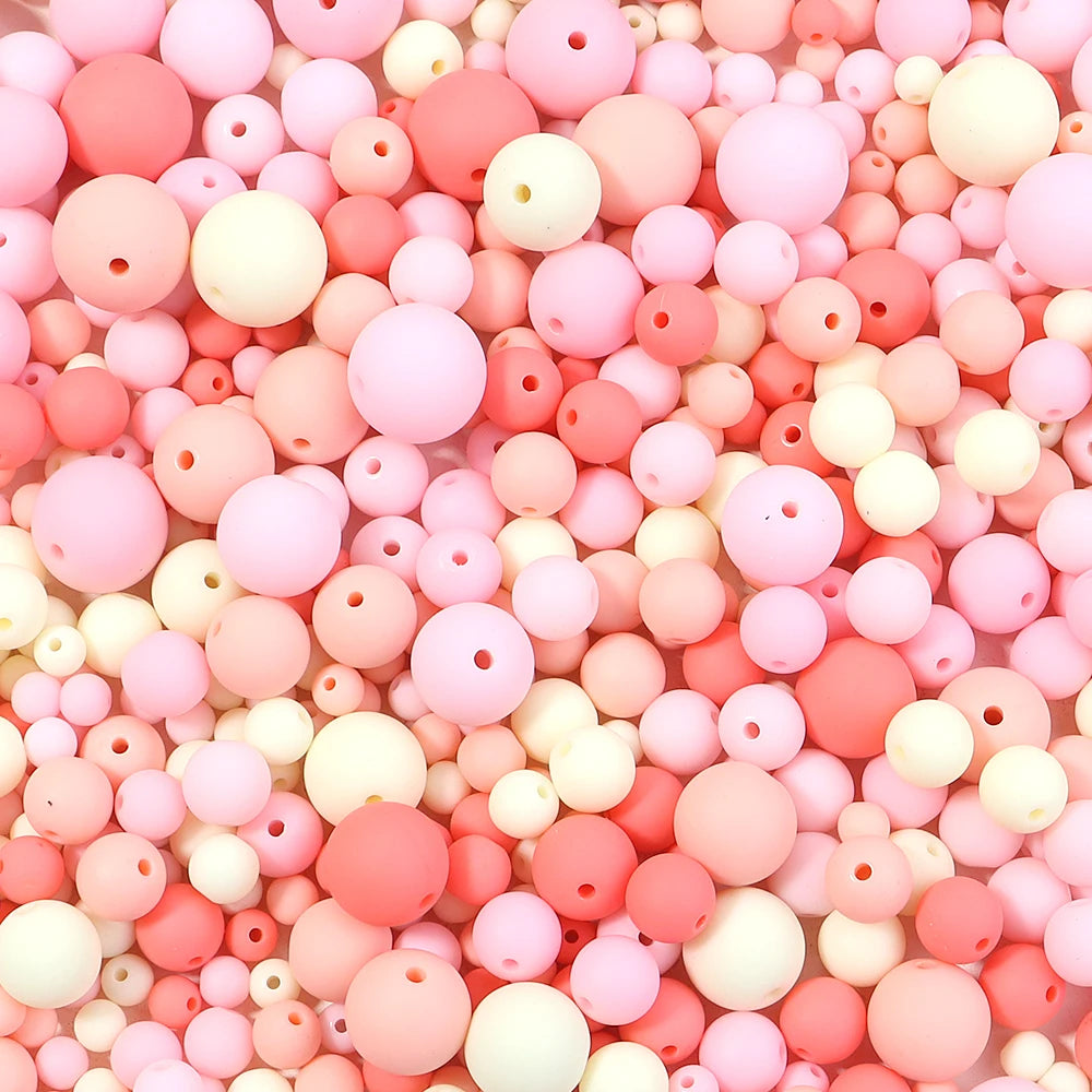 A close-up view of numerous matte acrylic beads in various shades of pink and white.