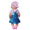 A doll wearing a pink cat print shirt and a blue denim dress with a pink patterned headscarf and pink boots.