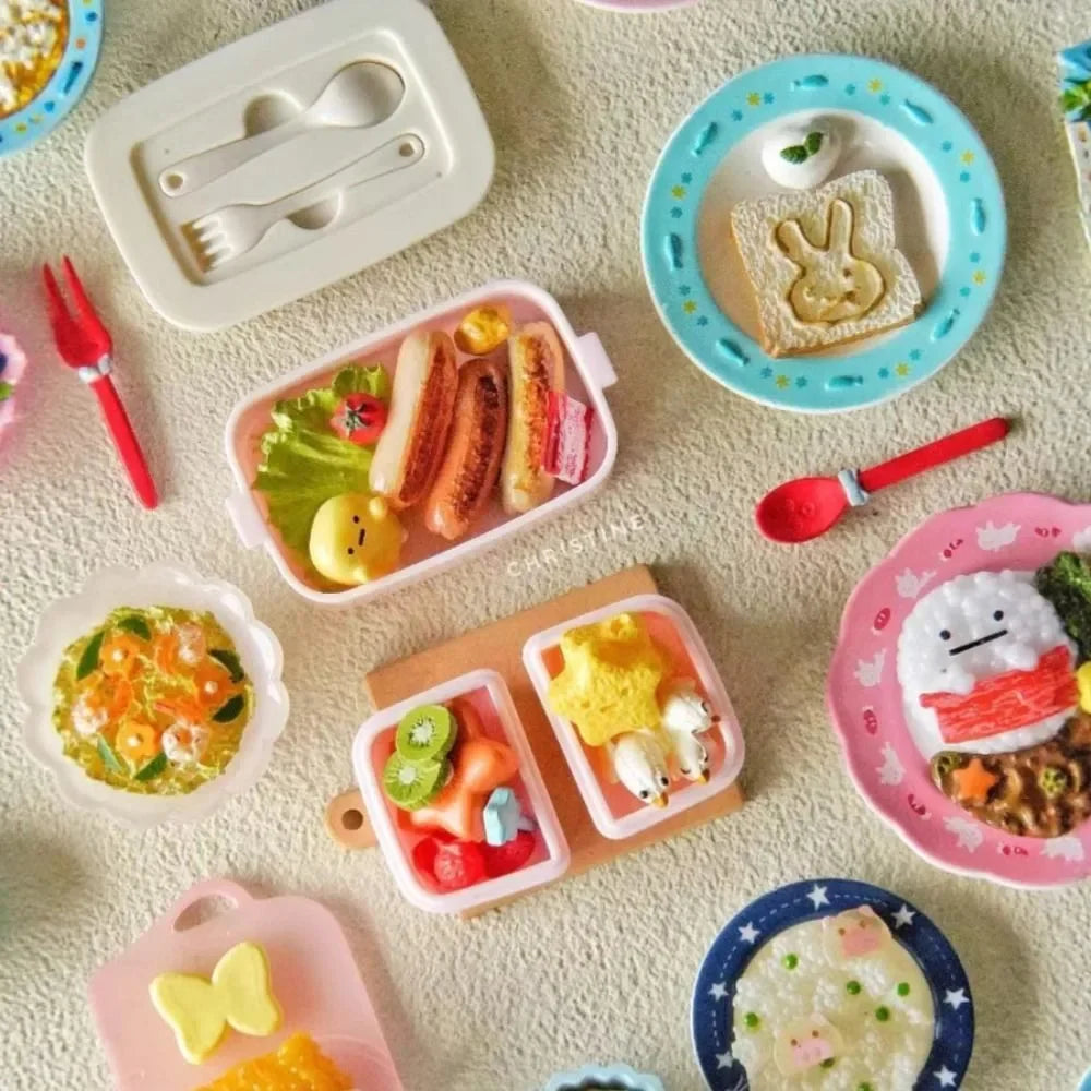 A collection of pink and white miniature food items, including sandwiches, fruit, and rice, arranged in various lunch boxes a