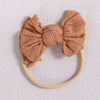 A light brown fabric bow headband with a thin beige elastic band.