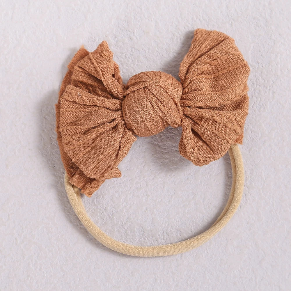 A light brown fabric bow headband with a thin beige elastic band.