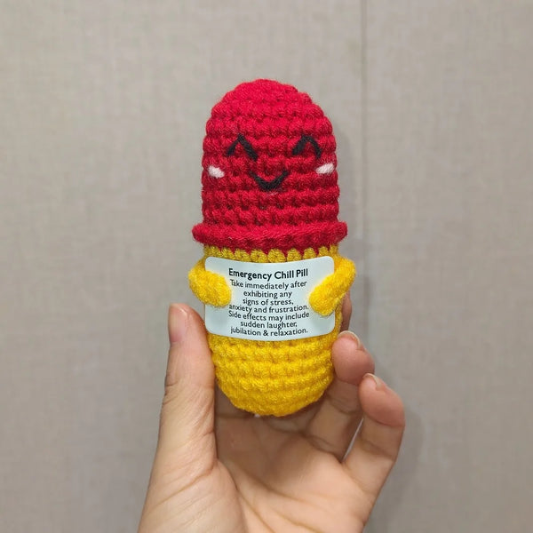A handmade crochet emergency chill pill charm shaped like a red chili pepper is held in a hand.