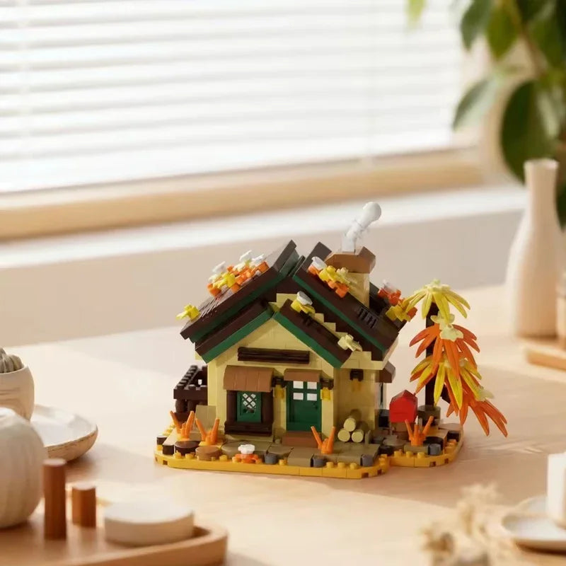 A miniature wooden cabin building set with a green roof and yellow walls sits on a light wood surface.