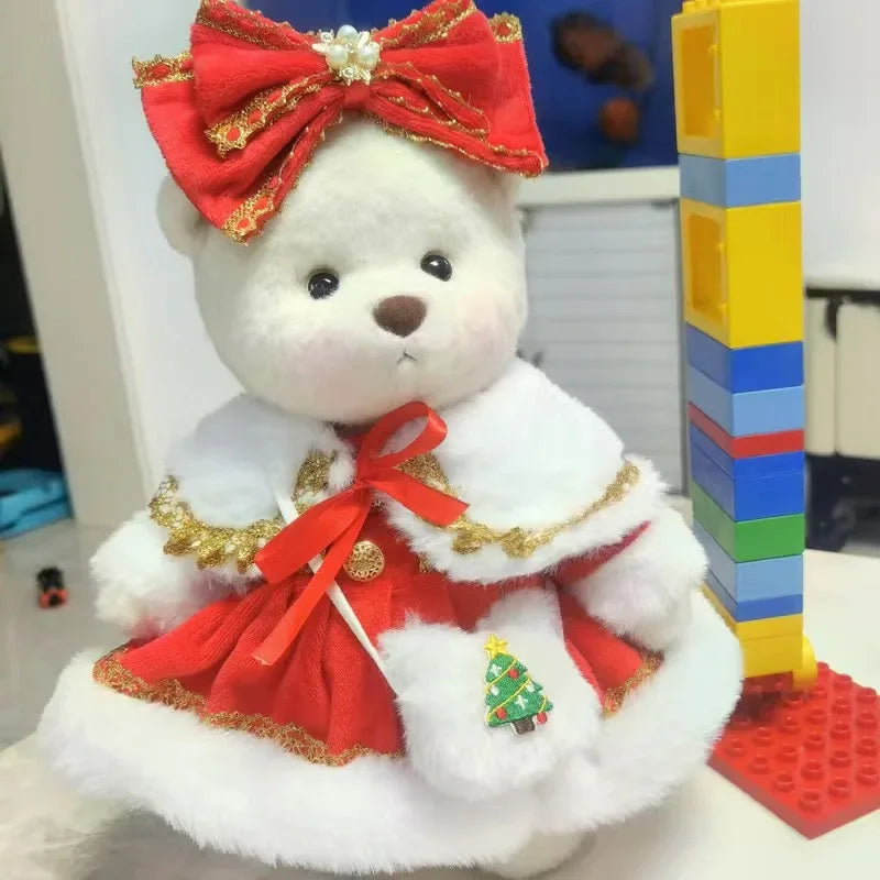 A white teddy bear plush wearing a red and gold dress with green accents.