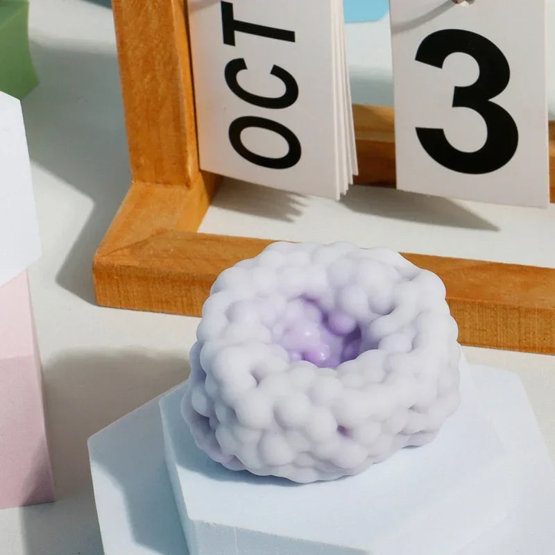 A white, squishy stress relief ball with a purple center is displayed in front of a wooden frame and numbered cards.