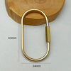 A brass keychain with a locking carabiner clip resting on a wooden surface.
