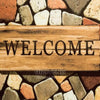 A wooden sign with the word WELCOME is placed on a background of multicolored stones.