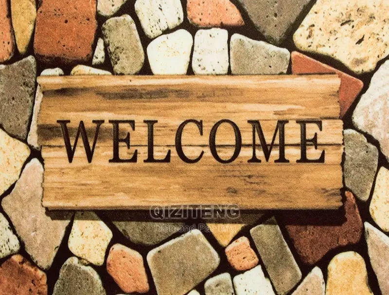 A wooden sign with the word WELCOME is placed on a background of multicolored stones.