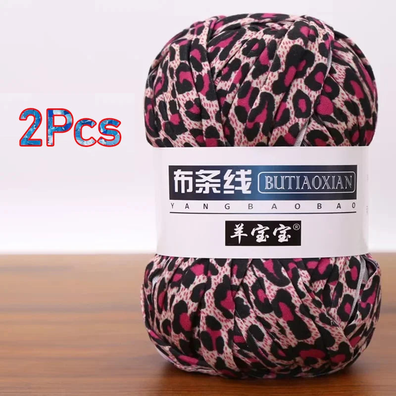 A skein of pink and black leopard print yarn labeled as Butiaoxian soft chunky t-shirt yarn for crochet and knitting, package