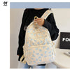 Un sac à dos de couleur crème clair avec un motif de nœud bleu est porté par une personne vêtue d'un haut noir.