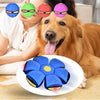 A dog looks at a human child holding colorful flying UFO pet toys with various colors.