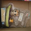 A clear plastic bag containing three small animal figures, including a light green cat and two other small toys.