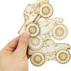 A hand holds several unfinished wood monster truck cutouts for DIY crafts.
