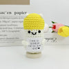 A yellow crocheted pencil ornament with a small heart tag sits on a wooden base.