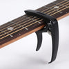 A black professional metal guitar capo with a pick holder clamped onto a wooden fretboard.