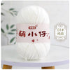 A ball of white chenille yarn with Chinese characters on the label displayed on a white table.