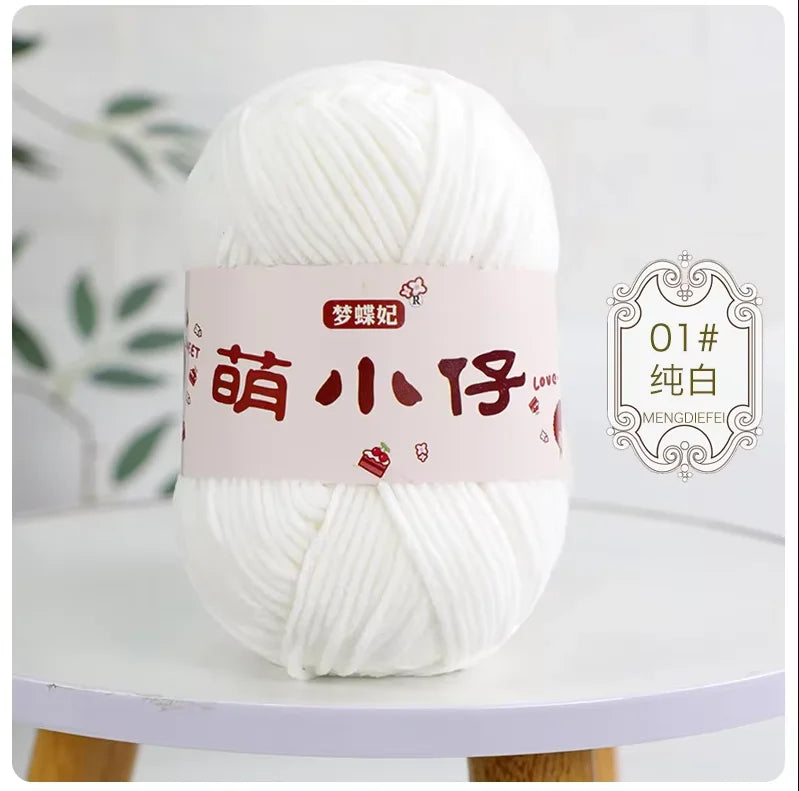 A ball of white chenille yarn with Chinese characters on the label displayed on a white table.