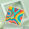 A framed piece of colorful wooden puzzle featuring rainbow-like wavy lines in various shades of blue, green, orange, and yell