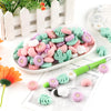A collection of pink, green, and white silicone flower and leaf beads for jewelry making displayed on a white plate.