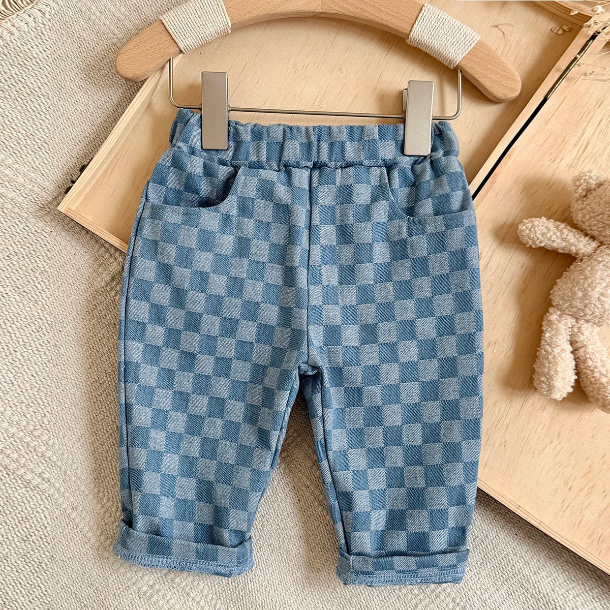 Light blue plaid corduroy pants for toddlers displayed on a wooden hanger.