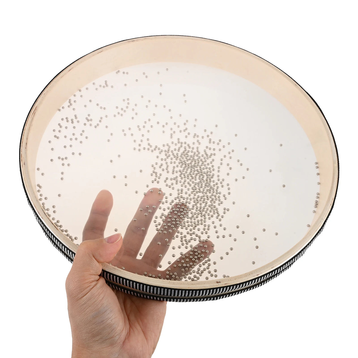 A hand holds a 12-inch ocean drum with a hardwood shell and carry bag, showing the interior surface covered in small beads.