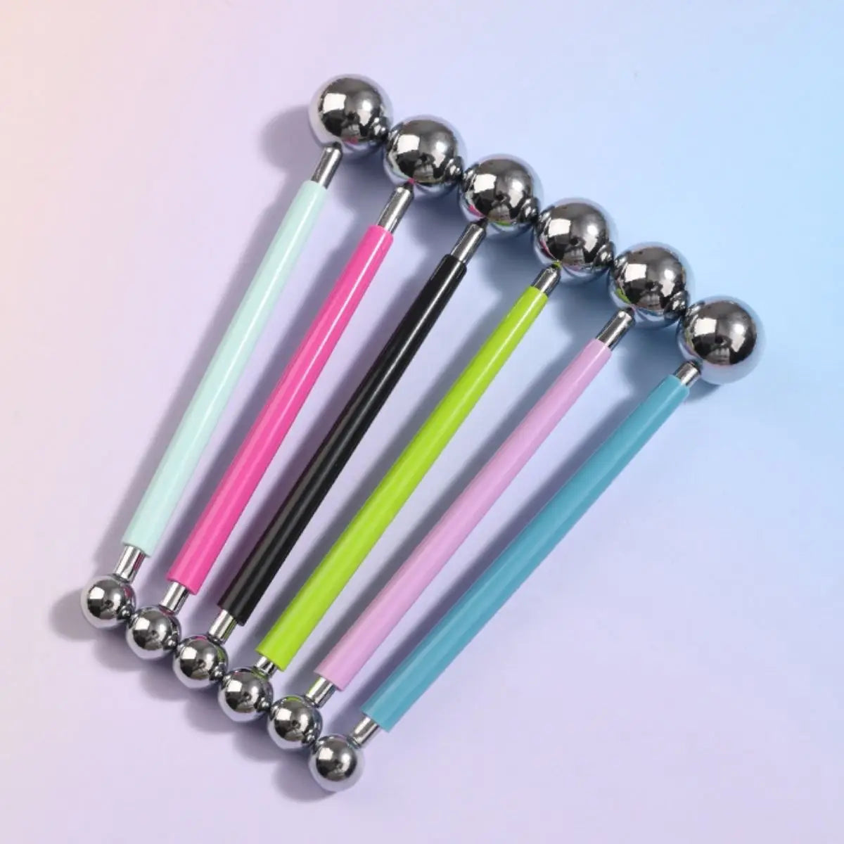 A set of four clay sculpting tools with silver balls and colored handles for pottery and crafting.