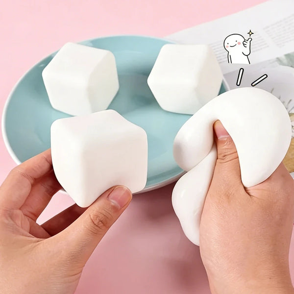 Eine Hand hält ein weißes, weiches Milch-Tofu-Fidget-Spielzeug auf einem hellblauen Teller.