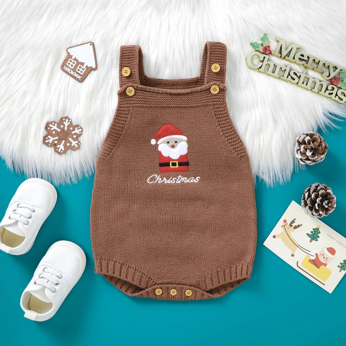 A brown knit baby romper with a red Santa embroidery and Christmas theme displayed on a white fluffy background.