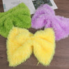 Three fluffy faux fur yarn skeins in lime green, purple, and yellow displayed on a wooden surface.