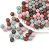 A collection of colorful printed silicone beads in various patterns and colors arranged on a white dish.