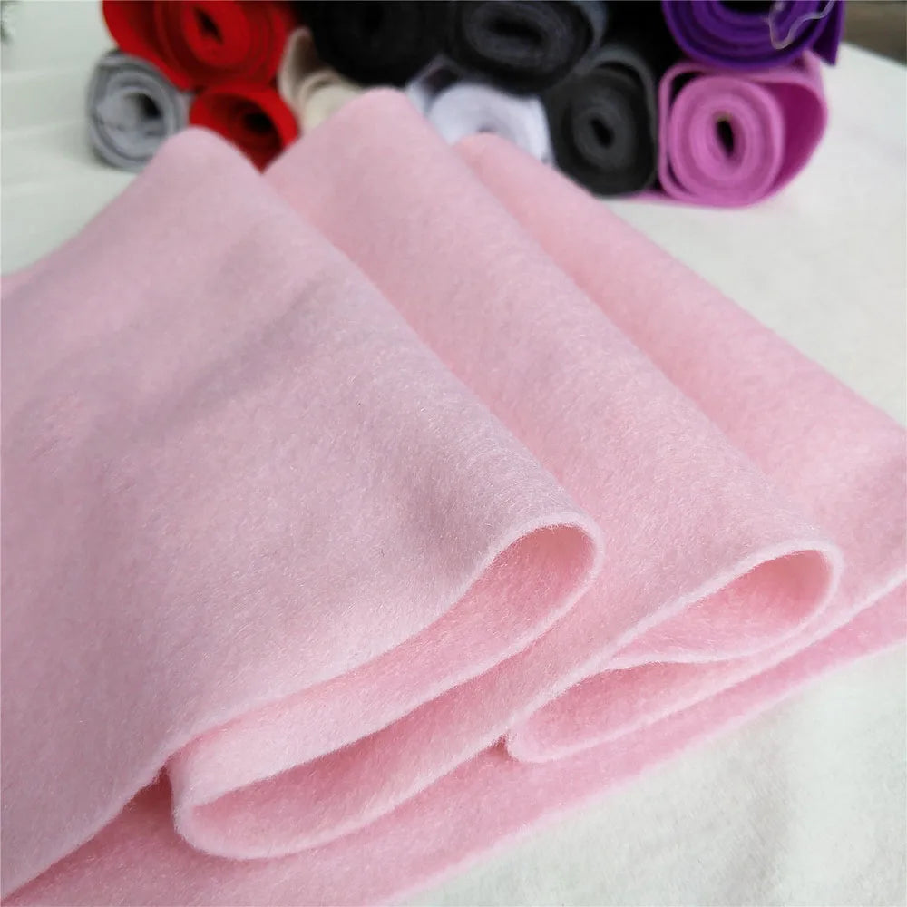 Pink felt fabric sheets rolled up next to various colored felt rolls for DIY crafts