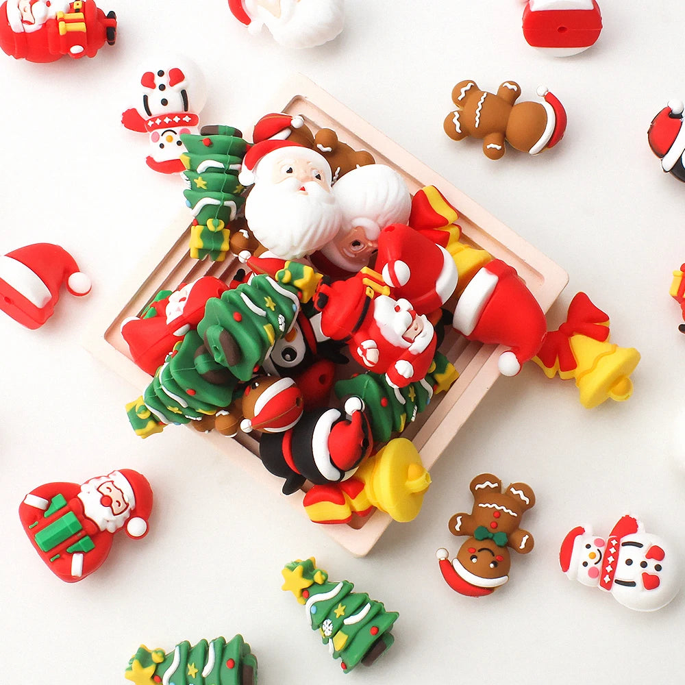 A collection of red and green silicone beads shaped like Santa, trees, and festive ornaments arranged on a wooden tray.