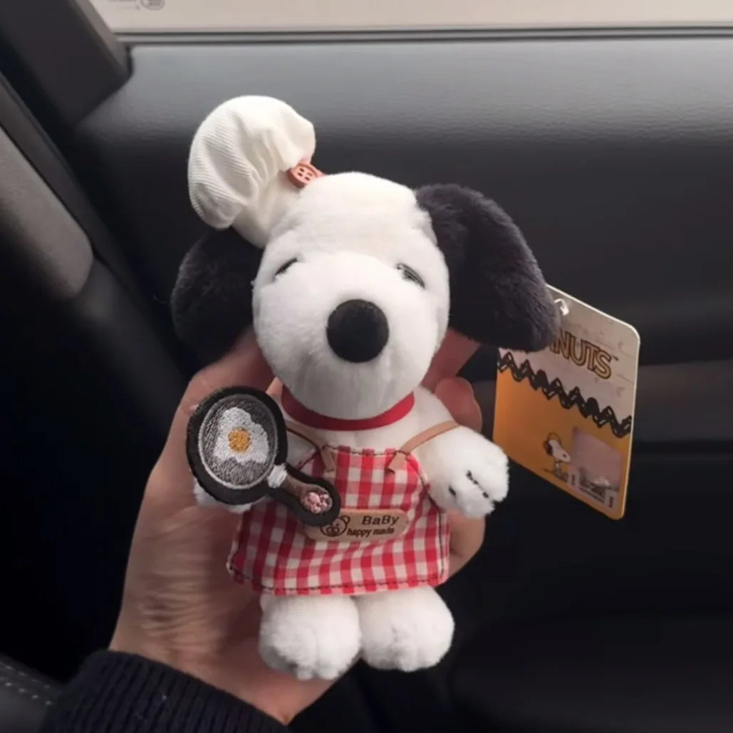 A white dog plush toy resembling Snoopy with a red collar and a tennis racket charm