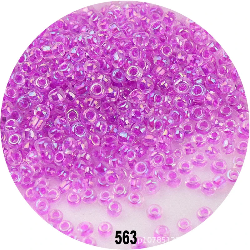 A close-up view of loose, round, colorful purple glass seed beads for jewelry making.