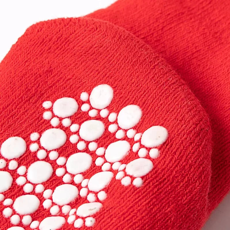 A close-up of a bright red knitted sock featuring white festive Christmas designs.