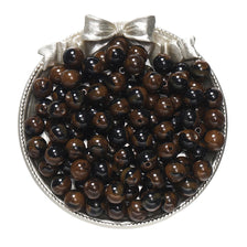A pile of dark brown and black round resin beads for jewelry making, tied with a silver bow.