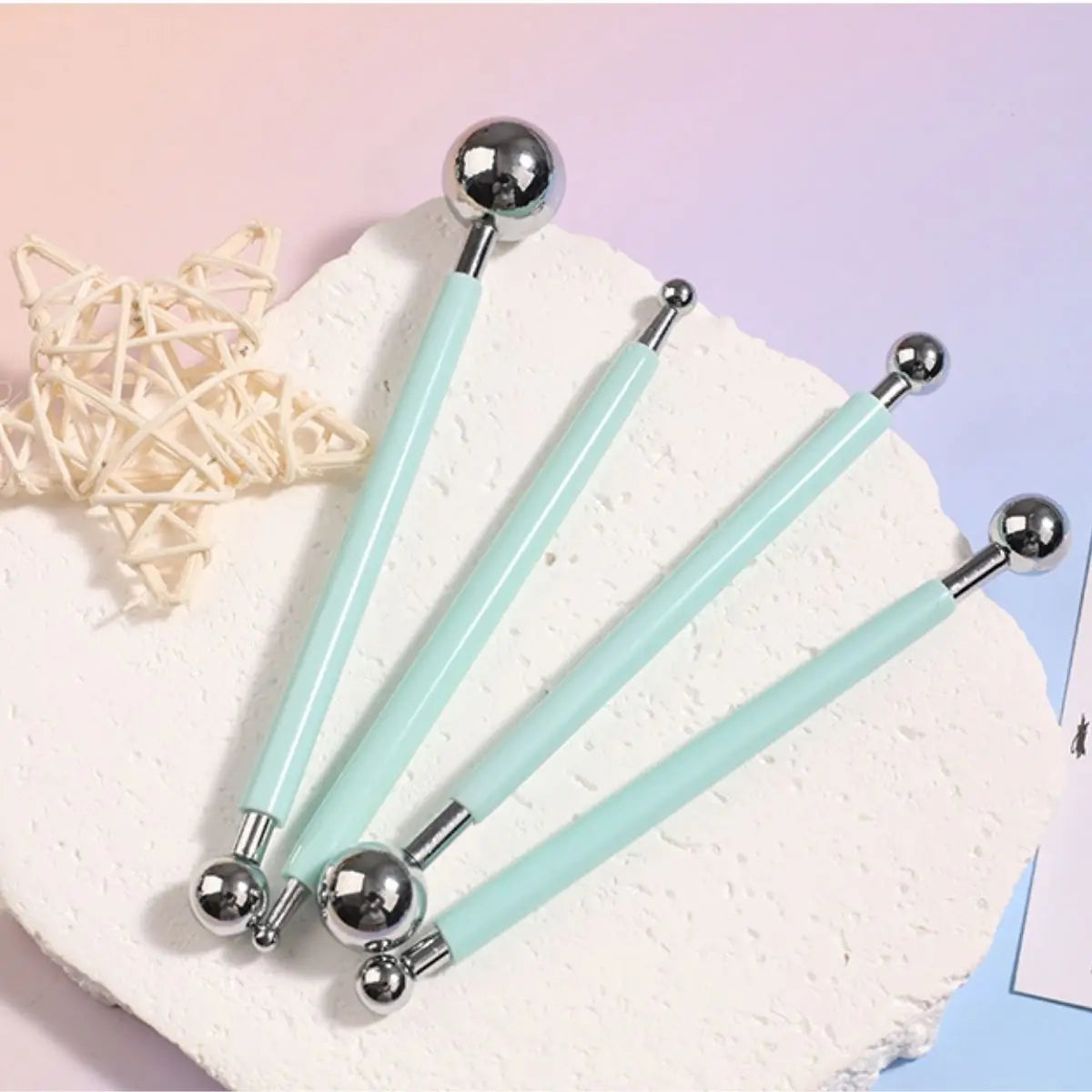 A set of four light blue clay sculpting tools with silver tips resting on a white surface.