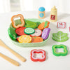 A wooden salad pretend play food set featuring various colored vegetables and a green bowl with wooden utensils.