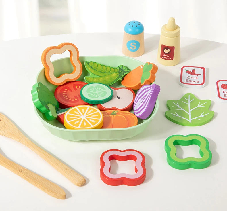 A wooden salad pretend play food set featuring various colored vegetables and a green bowl with wooden utensils.