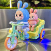 A cute blue rabbit electric tricycle with lights and music is shown on a silver surface.