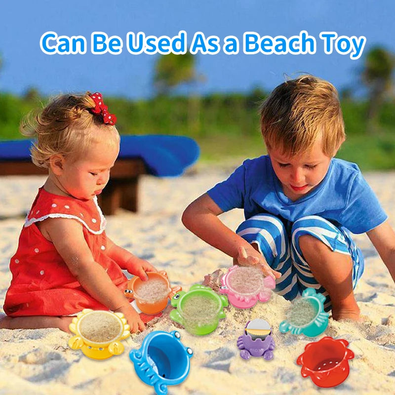 Two young children play with colorful stacking cups and floating boats in the sand.