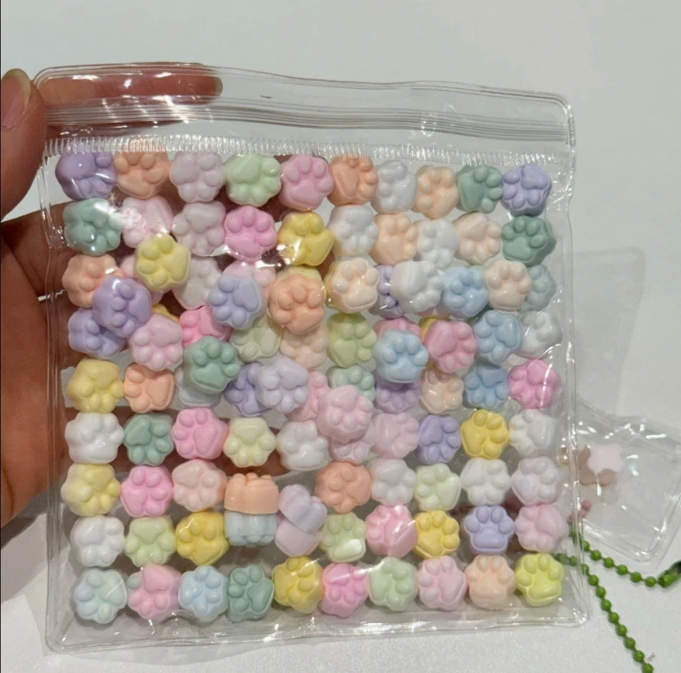 A clear plastic bag filled with numerous small, colorful squishy toys shaped like cat paws for stress relief.