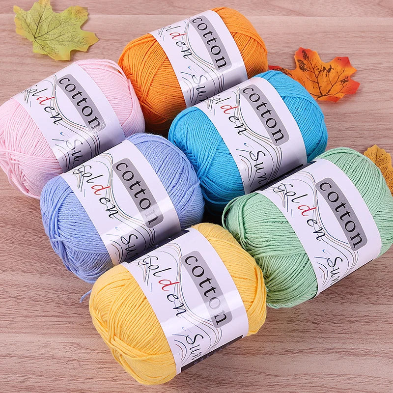 A collection of various colored pure cotton knitting yarn skeins in shades of orange, pink, blue, green, and yellow.