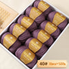 A box of purple Merino wool yarn balls with gold labels is shown for knitting projects.