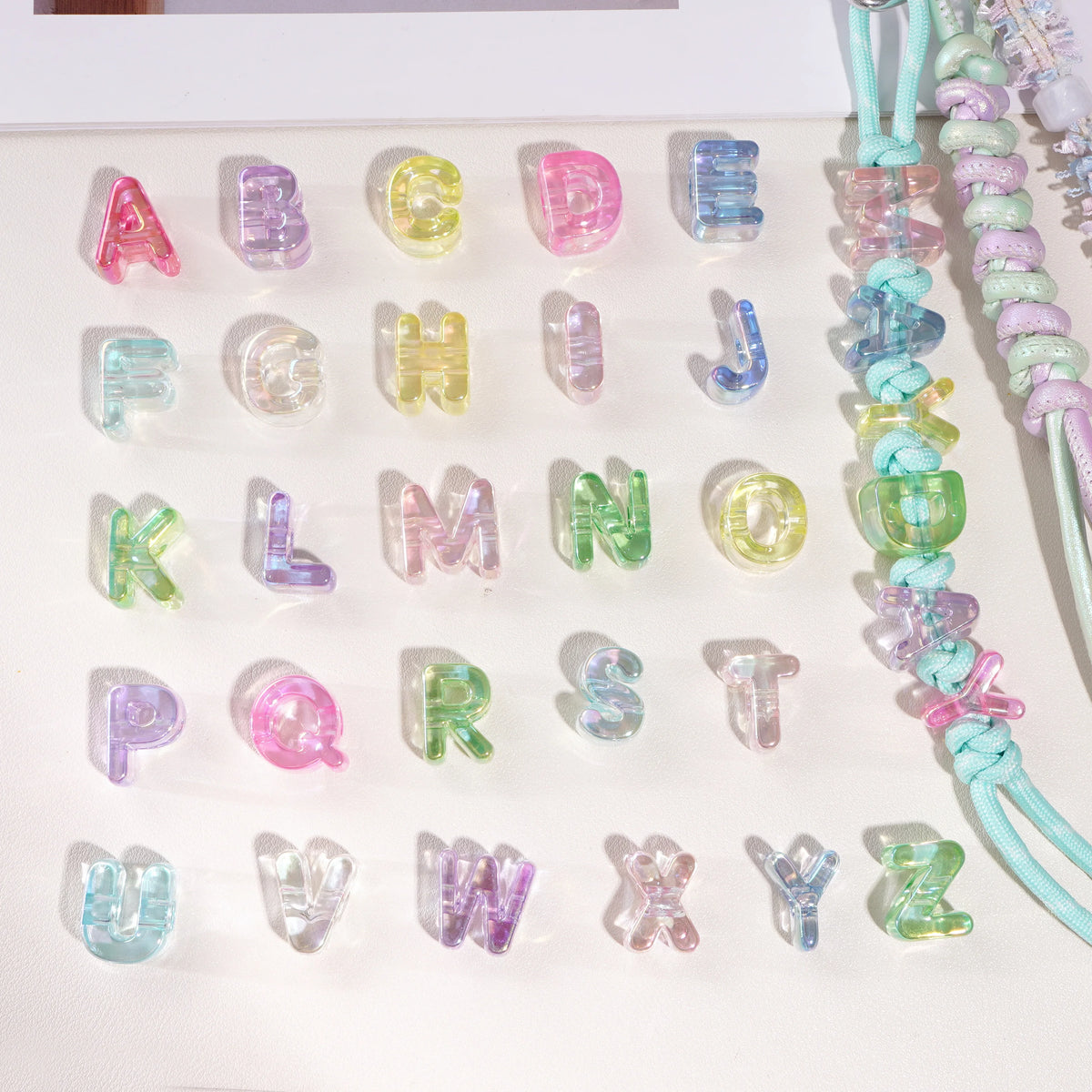 A display of colorful acrylic alphabet beads in various letters arranged on a white surface.