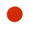 A clear container filled with bright orange Czech glass seed beads for jewelry making