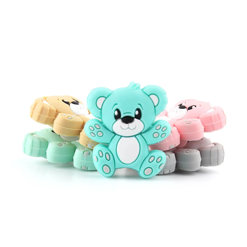 A collection of colorful silicone bear beads in various shades of mint green, pink, and beige for jewelry making.